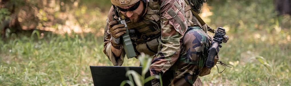 Military personnel in the field operating phone and computer off satellite network